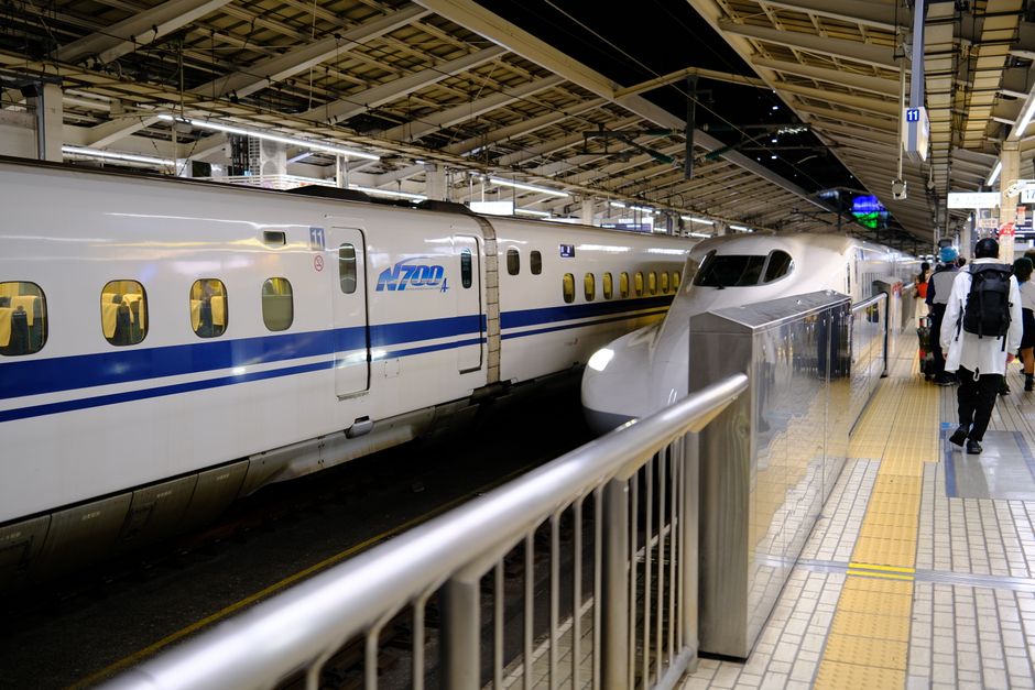 Shinkansen bullet train at a busy Tokyo station platform with passengers boarding.